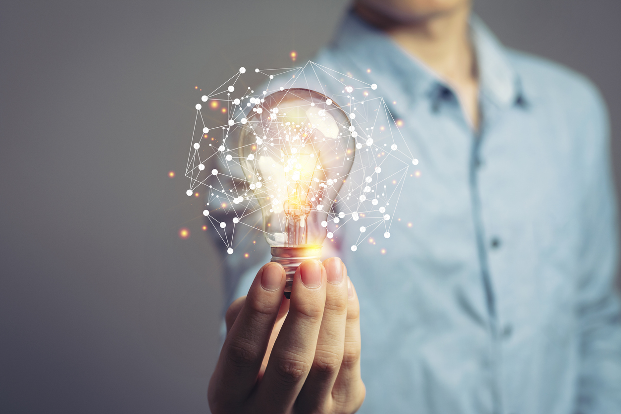 Person holding a glowing light bulb.