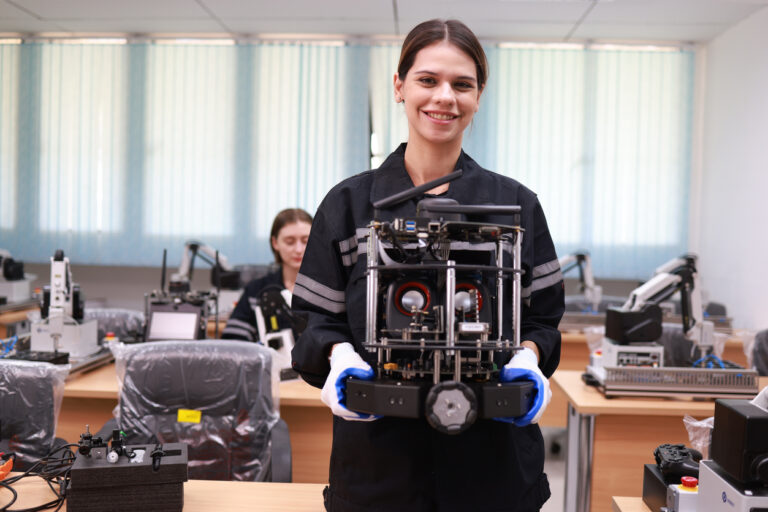 Woman holding robot in a classroom setting.